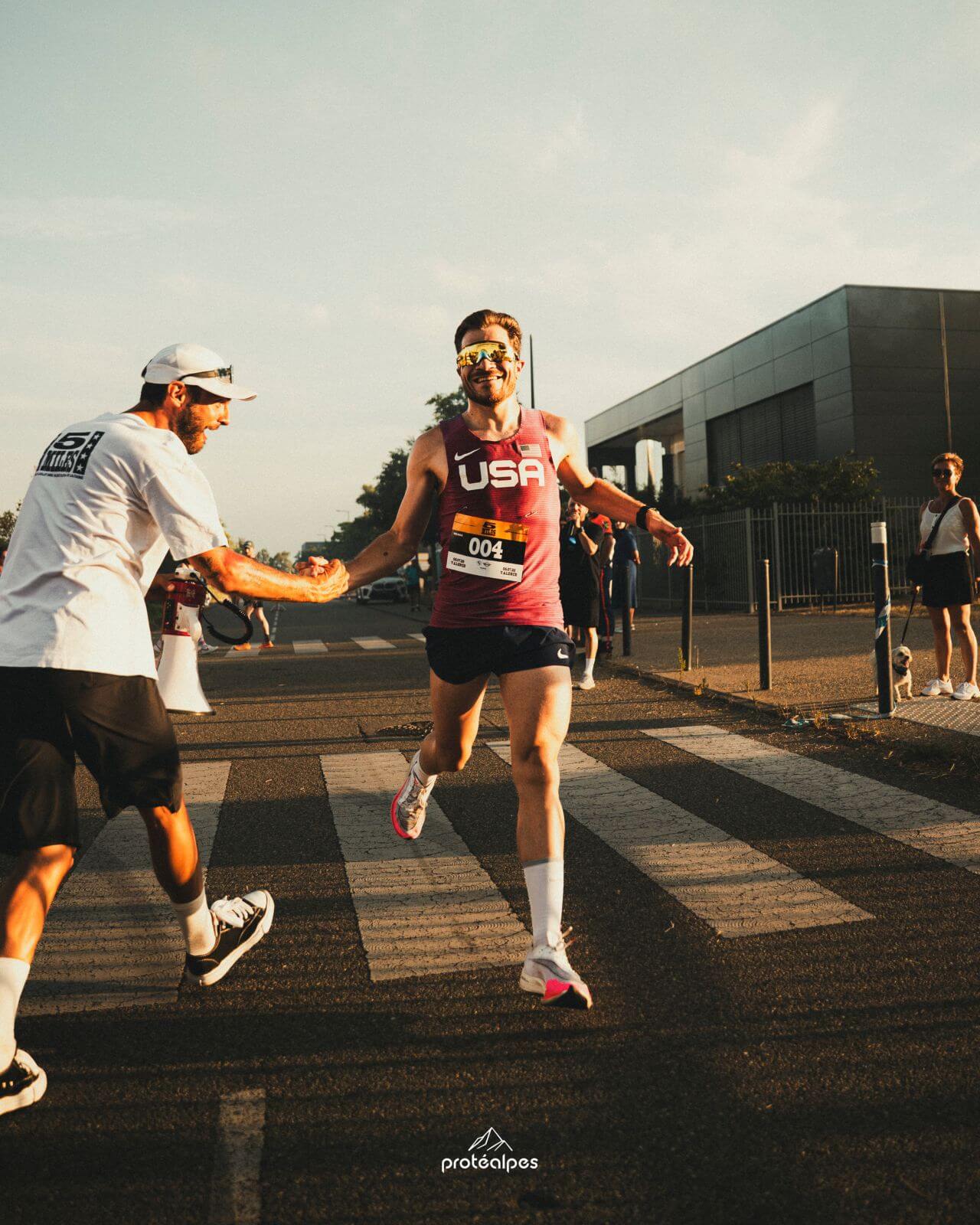 Un coureur reçoit une tape motivante pendant une course, symbolisant l'esprit sportif que Protéalpes valorise.