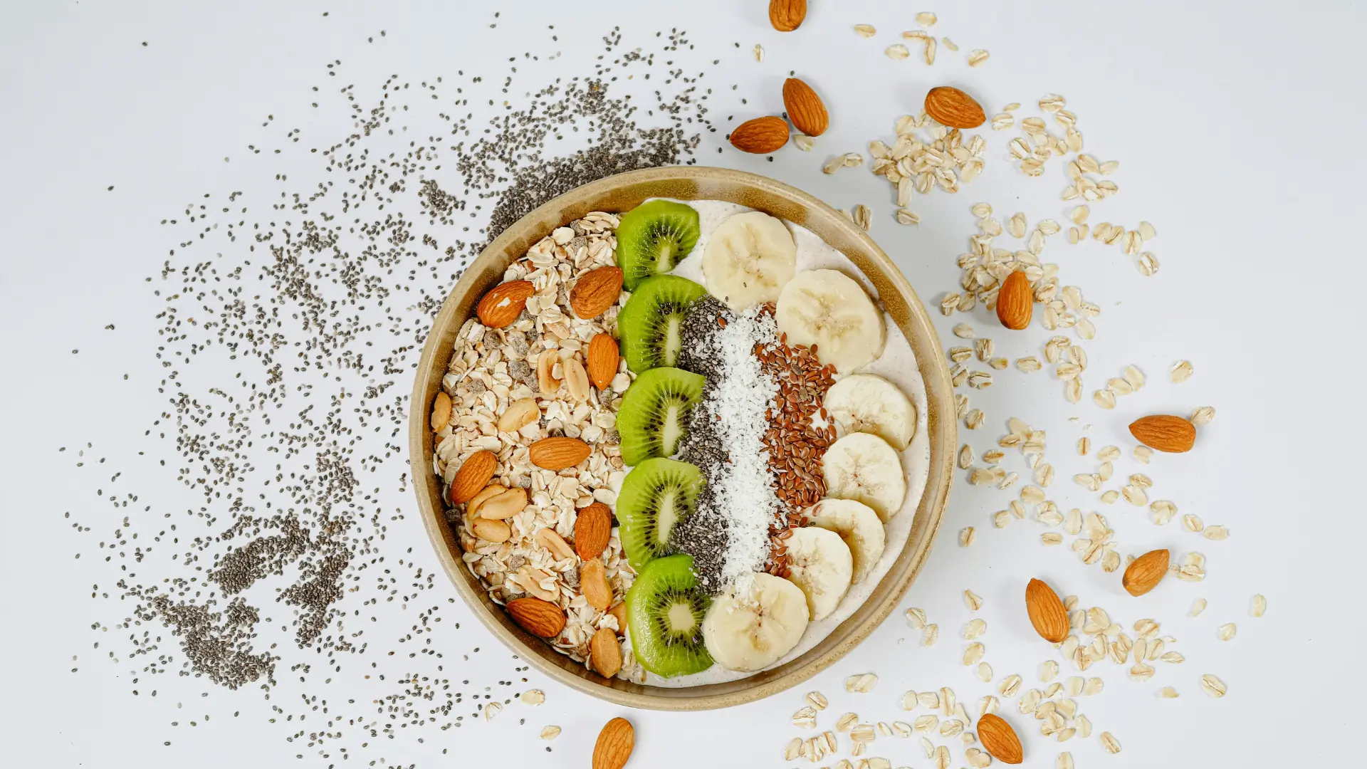 Bol de smoothie sain avec flocons d'avoine, amandes, kiwis, bananes et graines, idéal pour la nutrition sportive Protéalpes.