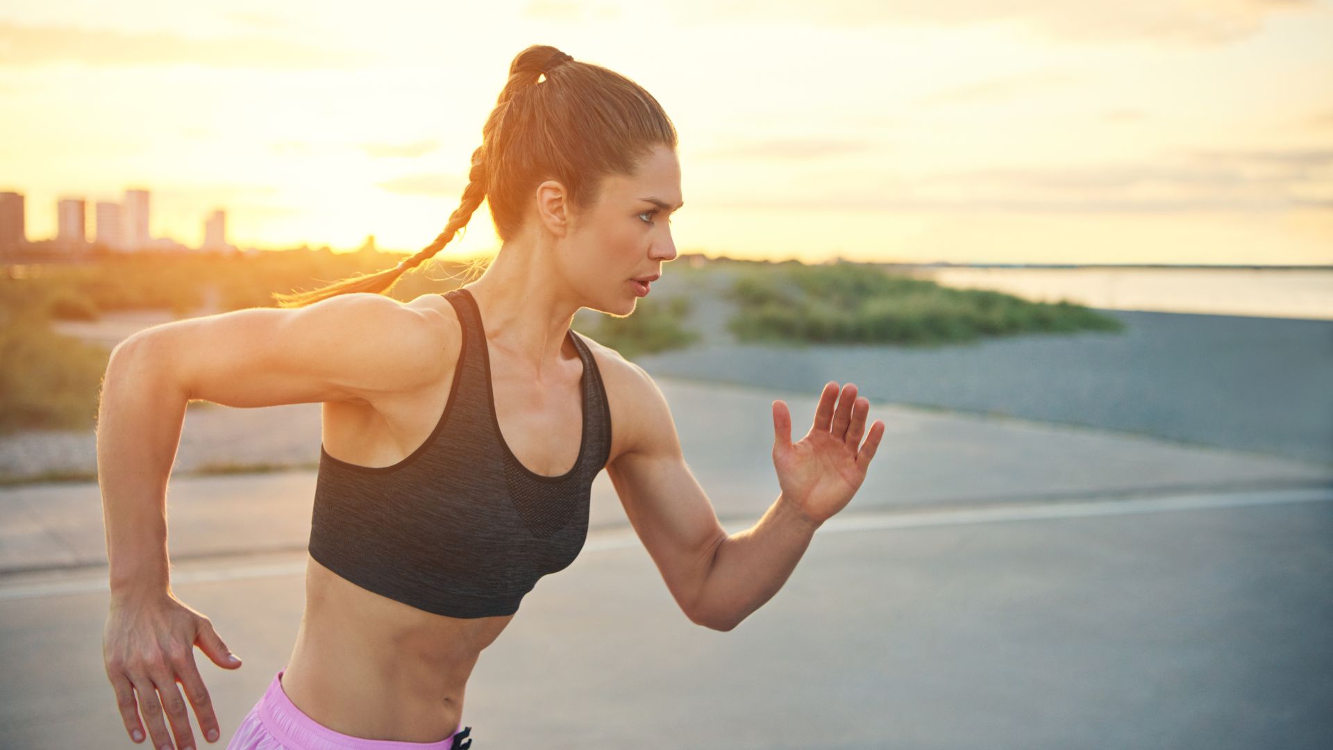 Woman in full effort during a sunset run, embodying vitality and natural athletic performance.