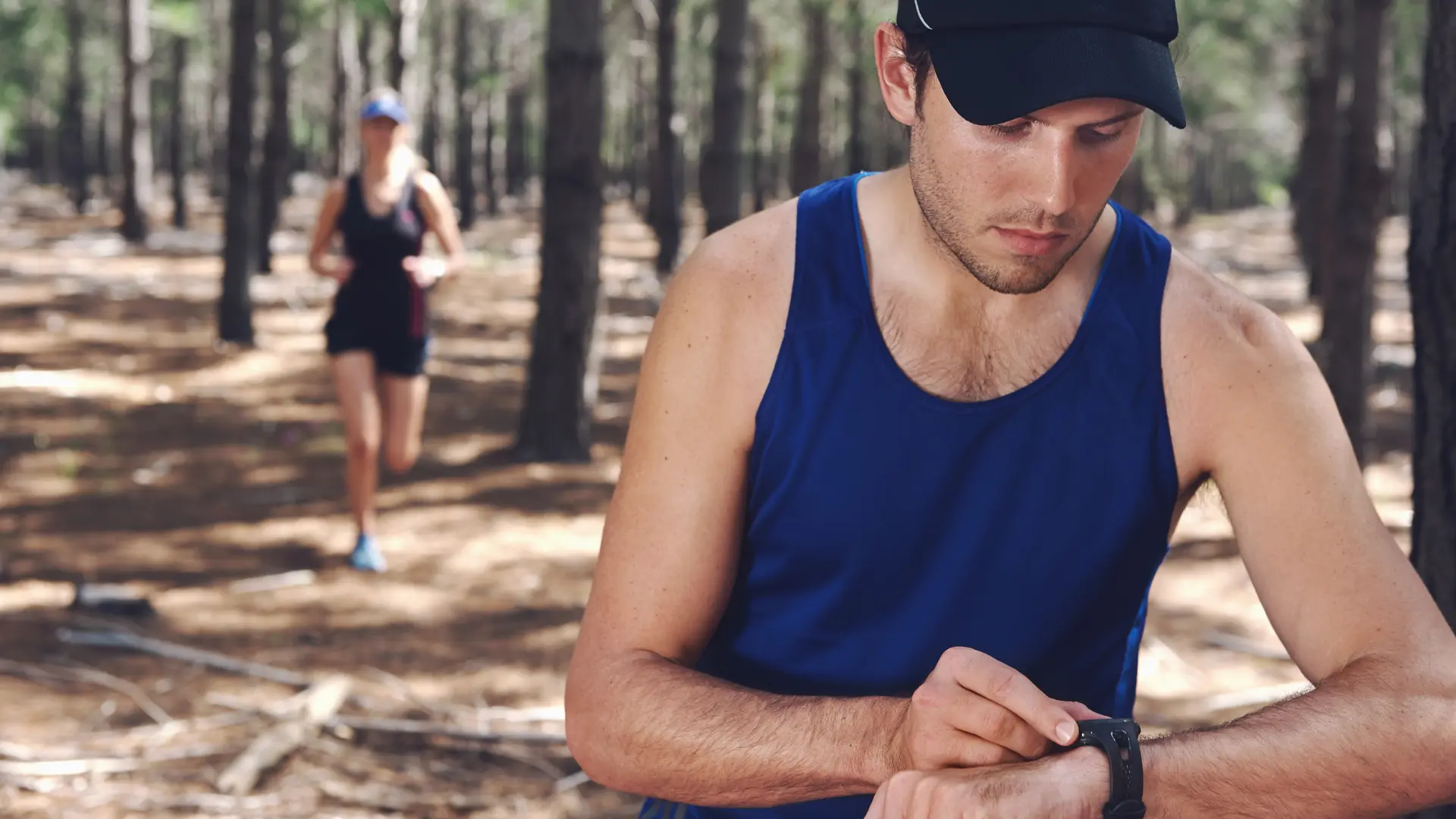 Man watching his watch while running in the forest, illustrating the natural, additive-free endurance promoted by Protéalpes.