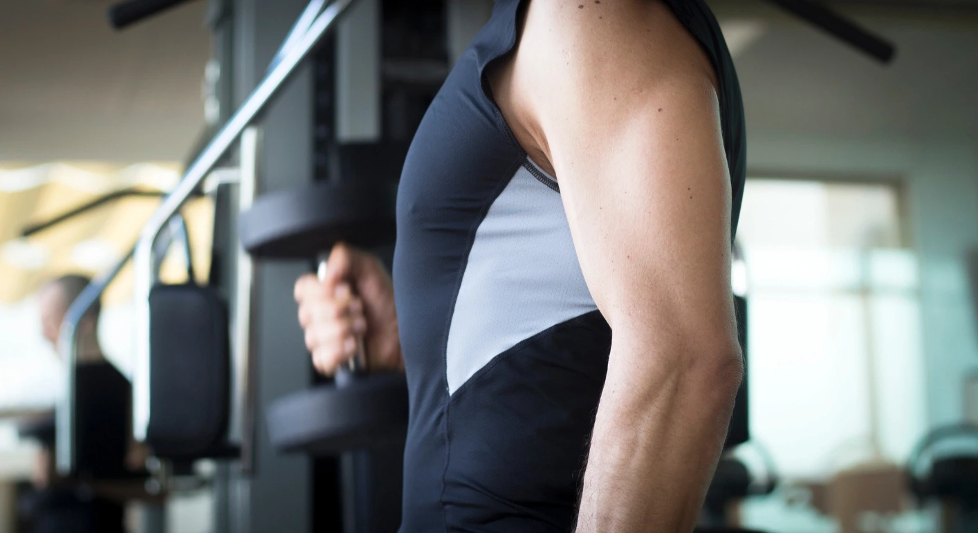 Athlète en salle de sport, bras musclé en action. Protéalpes: nutrition sportive sans édulcorants, sans additifs.