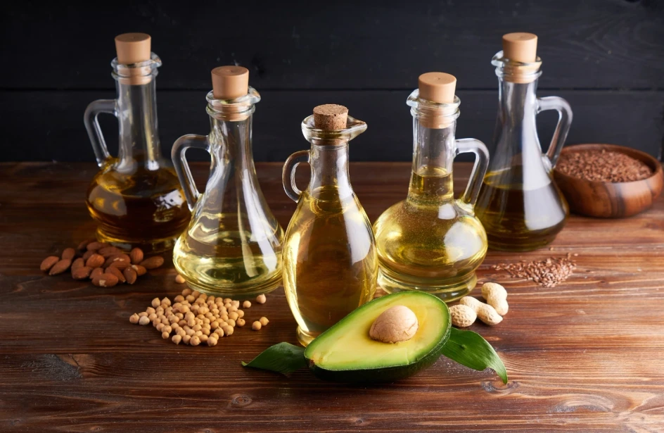 Huiles végétales naturelles et fruits secs sur une table en bois, symbolisant la nutrition sportive sans additifs de Protéalpes.