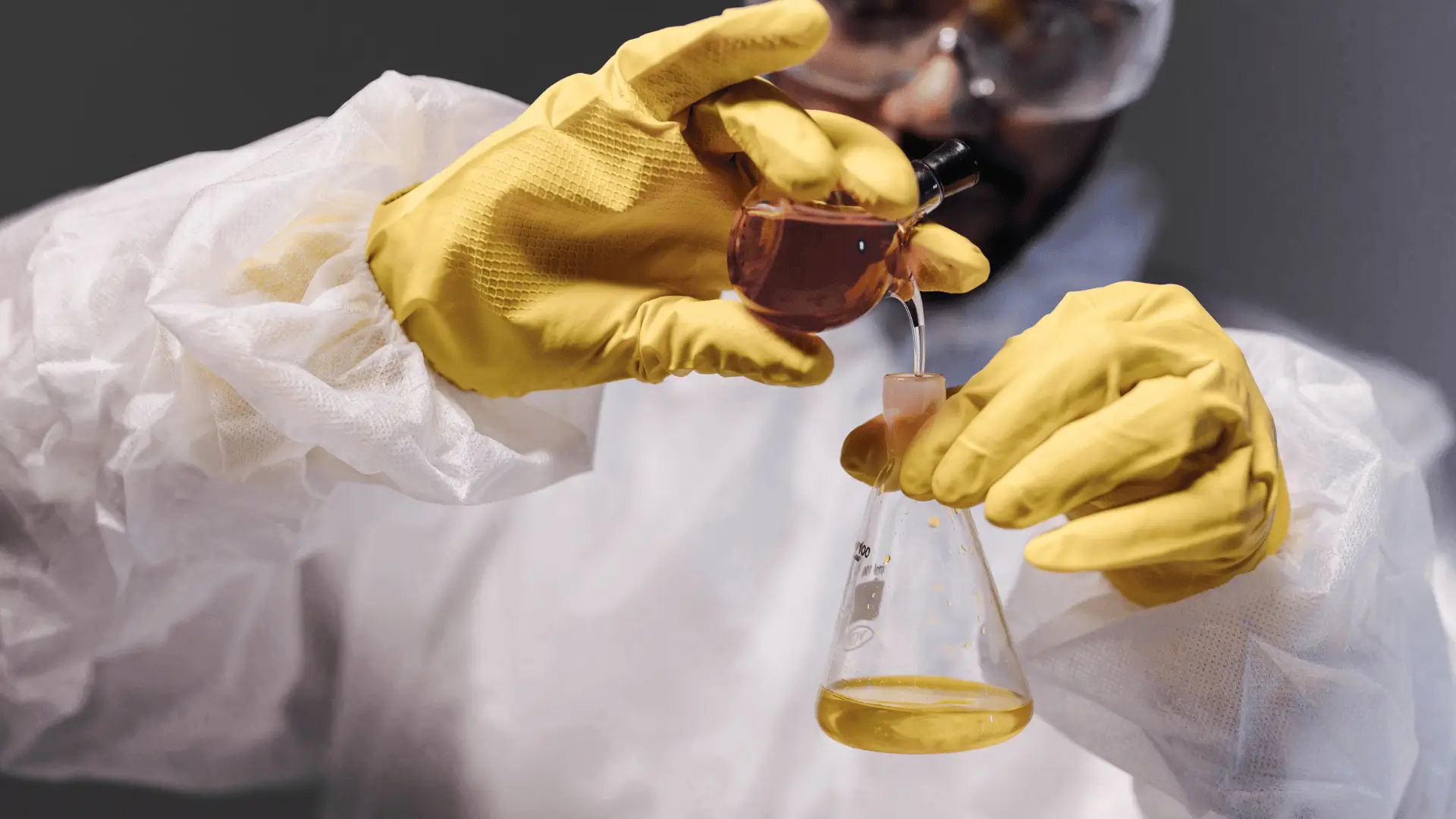 Wissenschaftlerin in gelben Handschuhen, die in einem Labor mit Flüssigkeiten hantiert und die Reinheit und Strenge von Protealpes veranschaulicht.