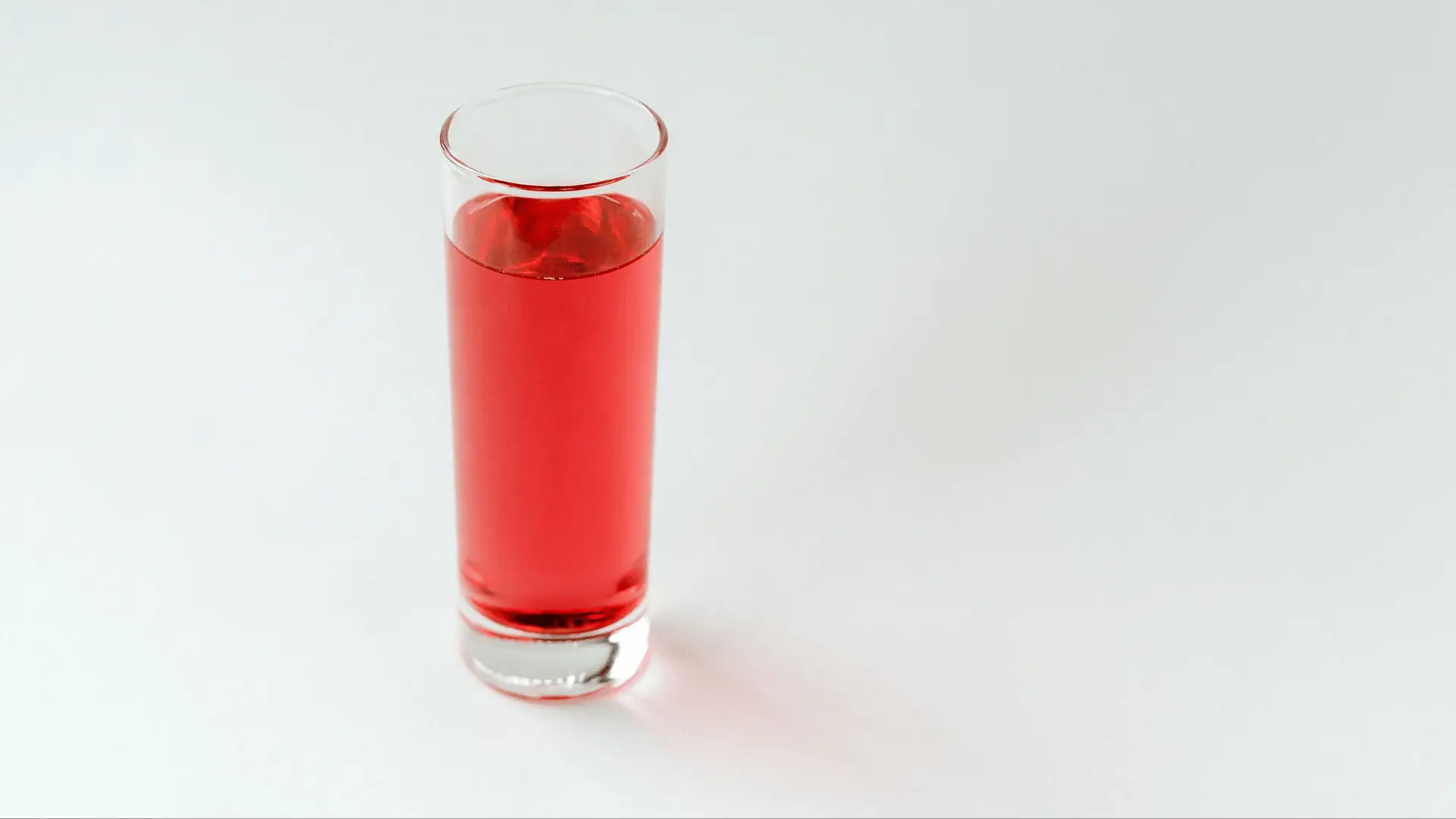 Rotes Trinkglas auf weißem Hintergrund, das das Engagement von Protéalpes für eine Sporternährung ohne Süßstoffe symbolisiert.