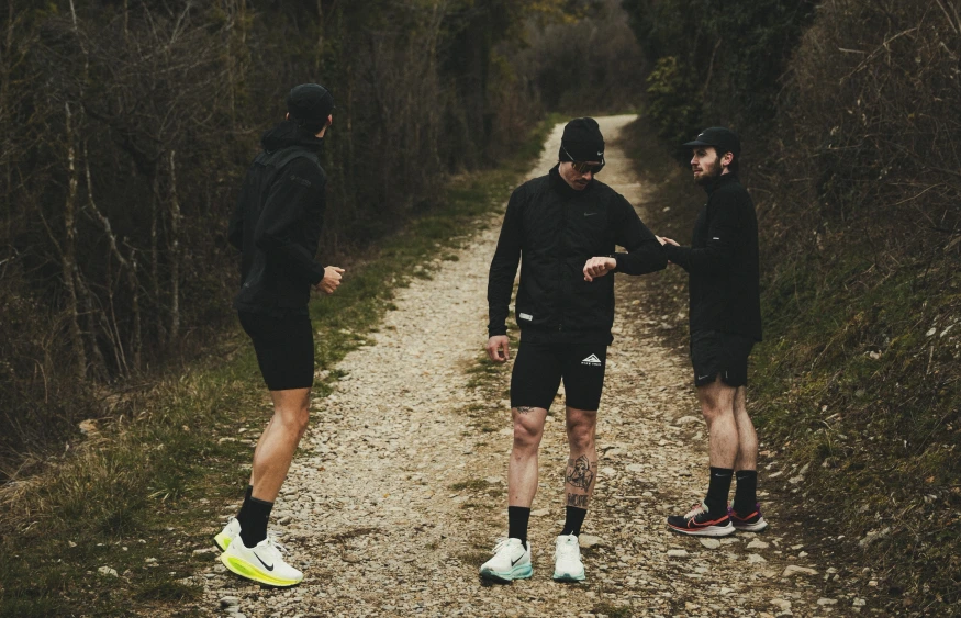 Three black-clad runners train outdoors on a path.