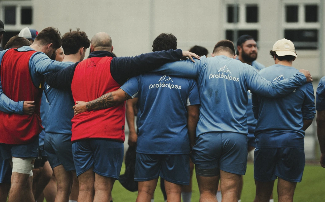 Joueurs de rugby en cercle, portant des vêtements Protéalpes, symbole de nutrition sportive sans additifs ni édulcorants.