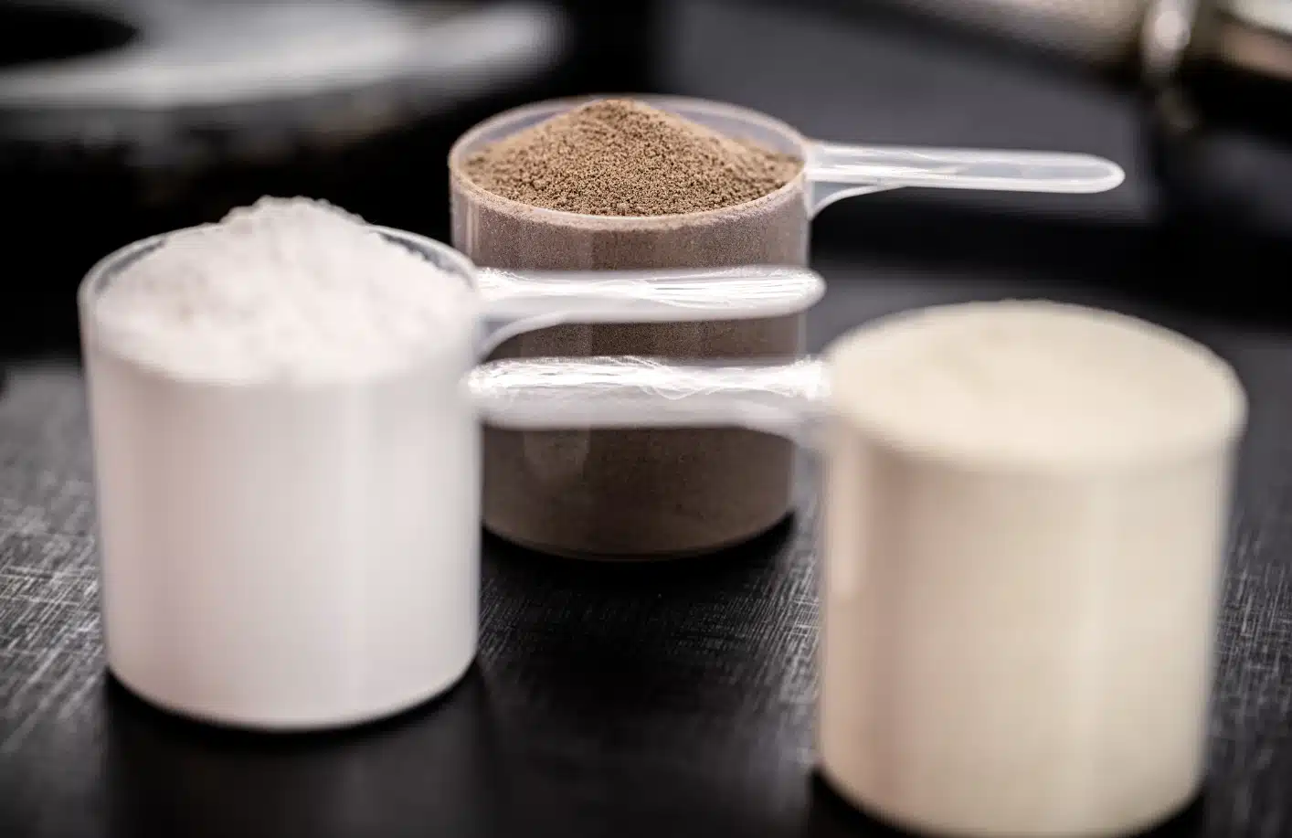 Trois portions de poudres protéinées naturelles, sans édulcorants ni additifs, illustrant une nutrition sportive saine.