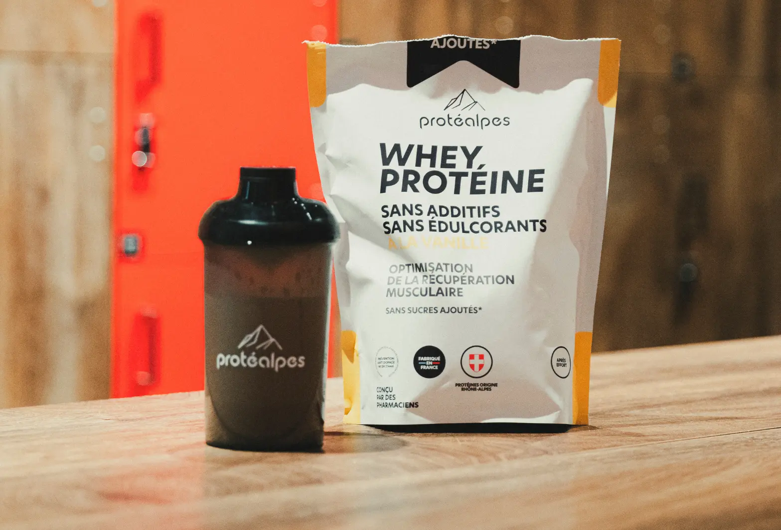 Protéalpes whey protein bag and shaker on a table, with no additives or sweeteners, for pure sports nutrition.
