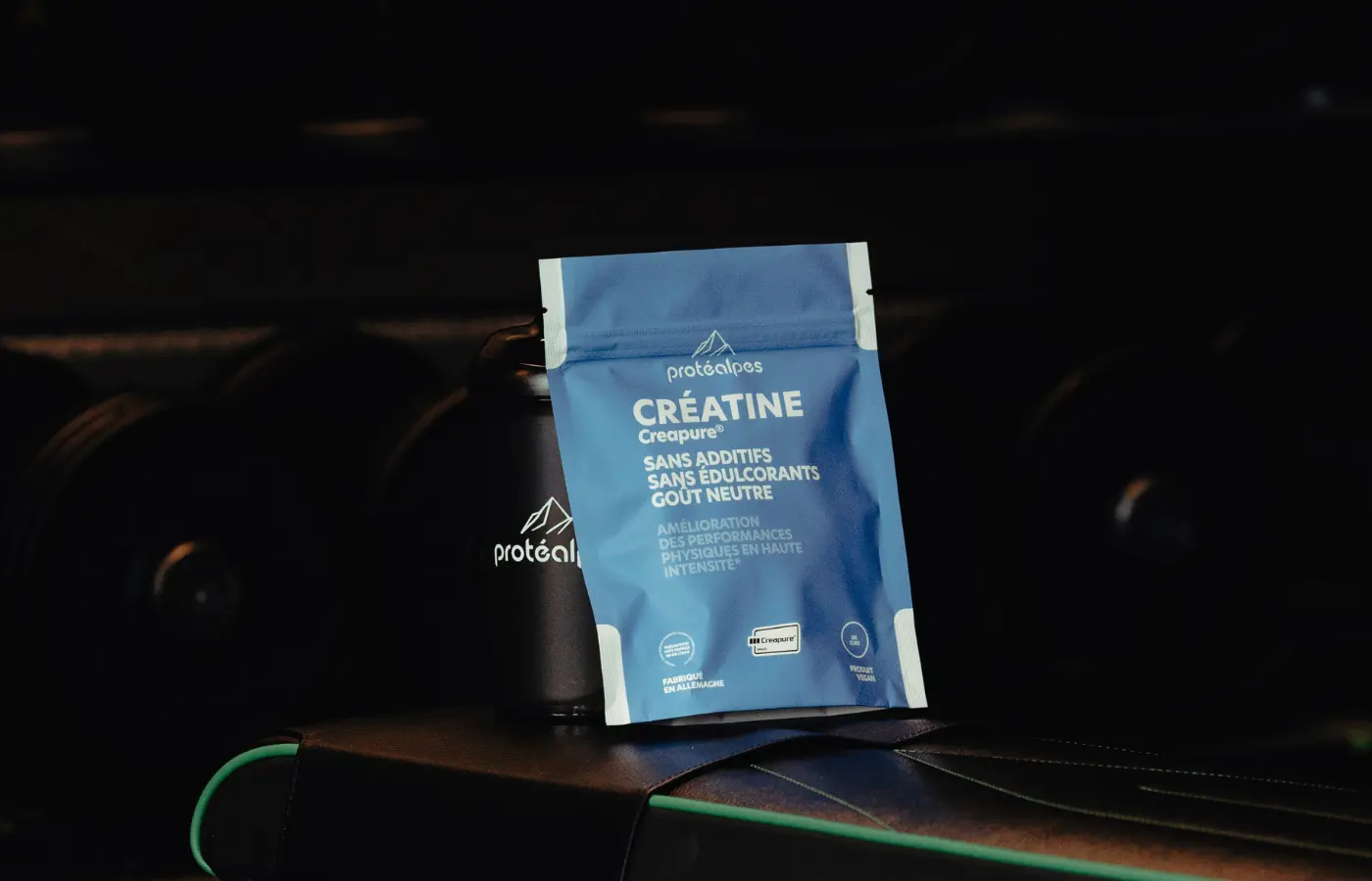 Protéalpes creatine product, free of additives and sweeteners, set against a backdrop of sports equipment, for high-end sports nutrition.