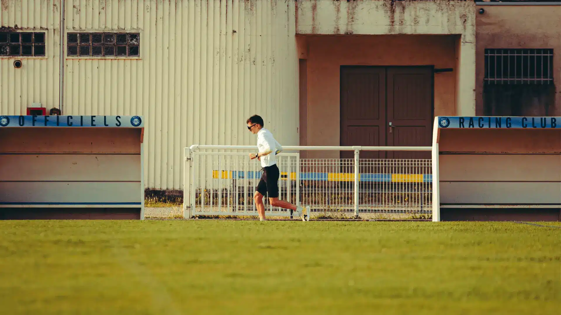 Athlete running on a track in front of a building, illustrating uncompromising performance with Protéalpes.