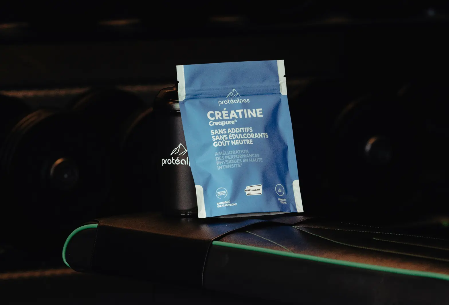 Emballage de créatine Protéalpes sur un banc de musculation, sans additifs ni édulcorants, destiné à une nutrition sportive de qualité.