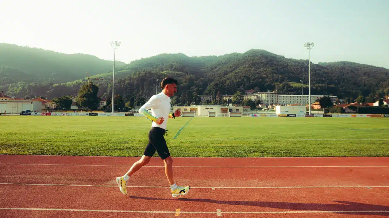An athlete runs on a track surrounded by greenery, symbolizing Protéalpes' pure, additive-free sports nutrition.